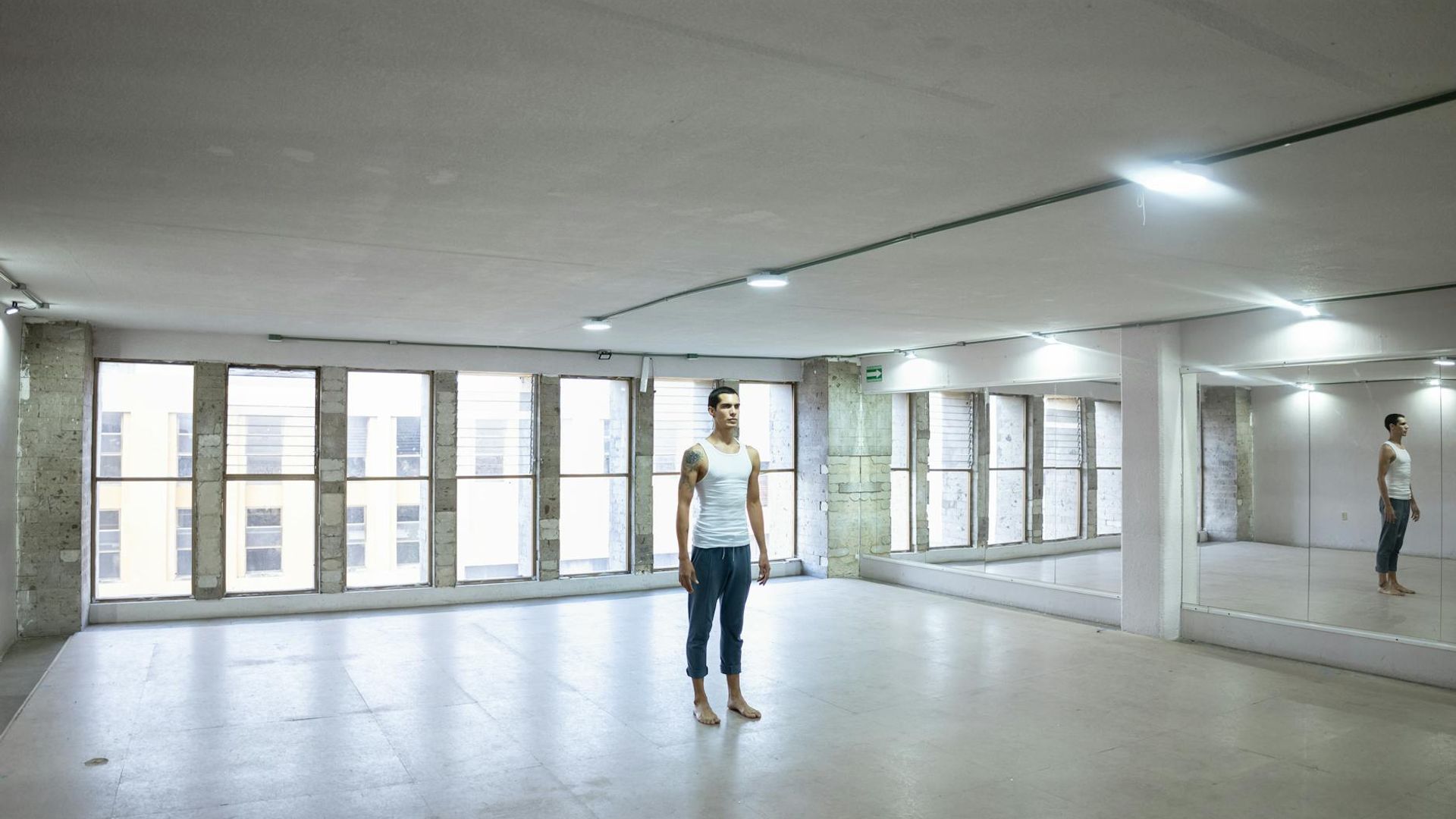 Person practicing yoga in a bright studio with large windows.